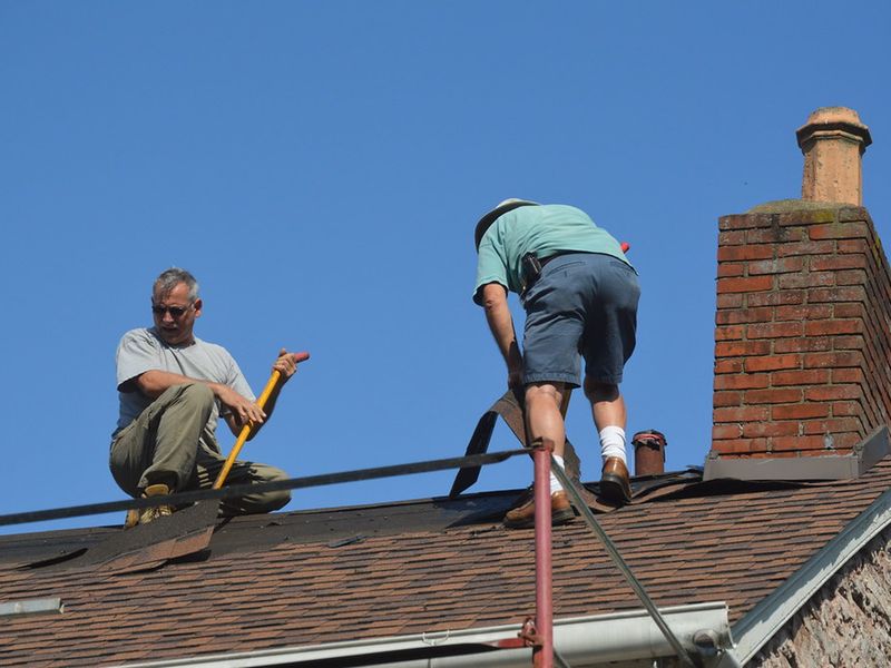 Roofers repairing a shingle roof