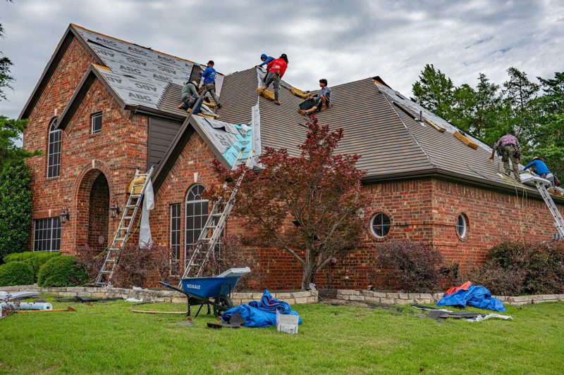 Roofing crew tearing off old shingles during a roof replacement in Nashville, TN